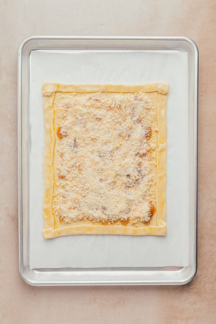 Puff pastry rolled out on a baking sheet with the edges turned in to make a crust and parmesan cheese sprinkled over top.