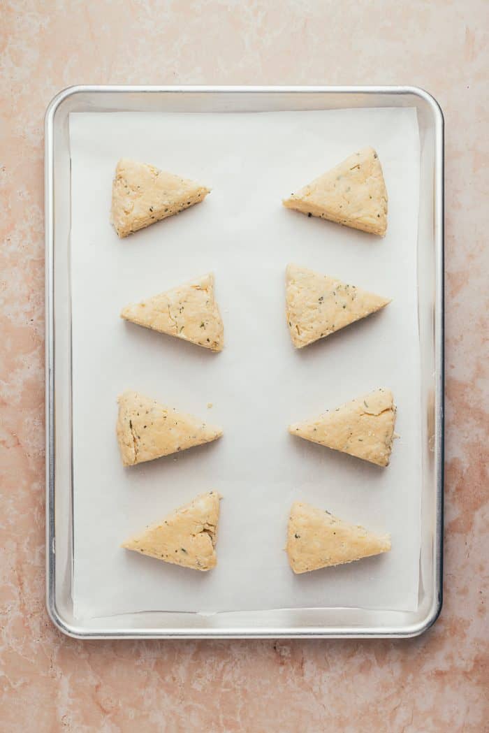 The unbaked scones on a parchment-lined baking sheet.