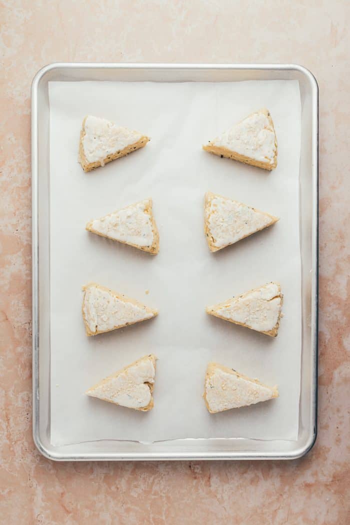 The unbaked scones on a parchment-lined baking sheet.