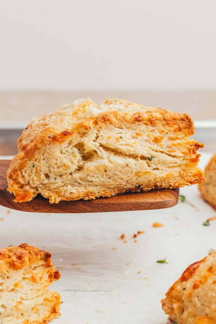 A wooden spatula with a savory scone on it.