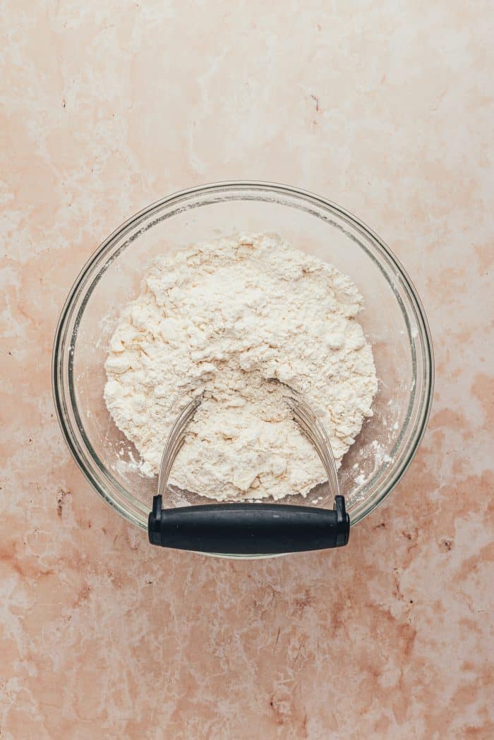 A glass bowl with butter and flour mixed together. 