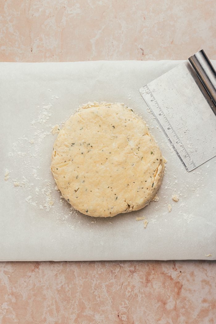 The scone dough in a disk shape on parchment paper.