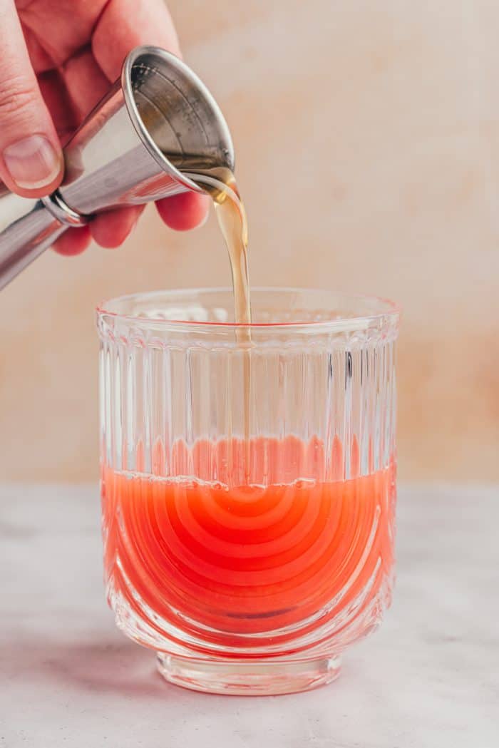 Rosemary honey syrup being added to the blood orange juice.