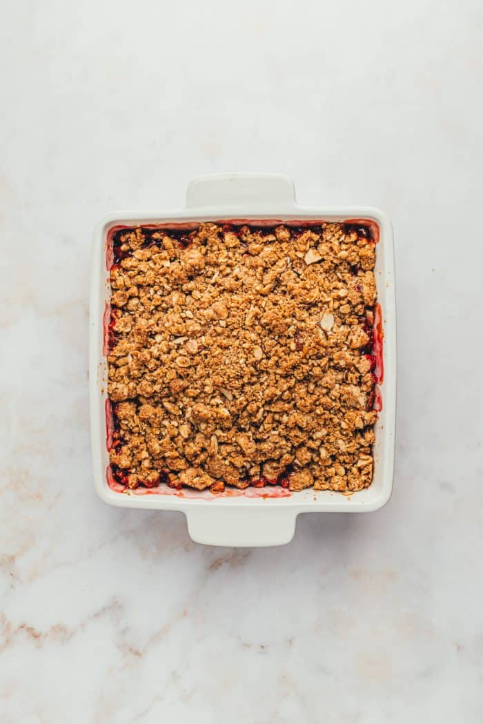 A square white baking dish with a baked pear cranberry crumble.