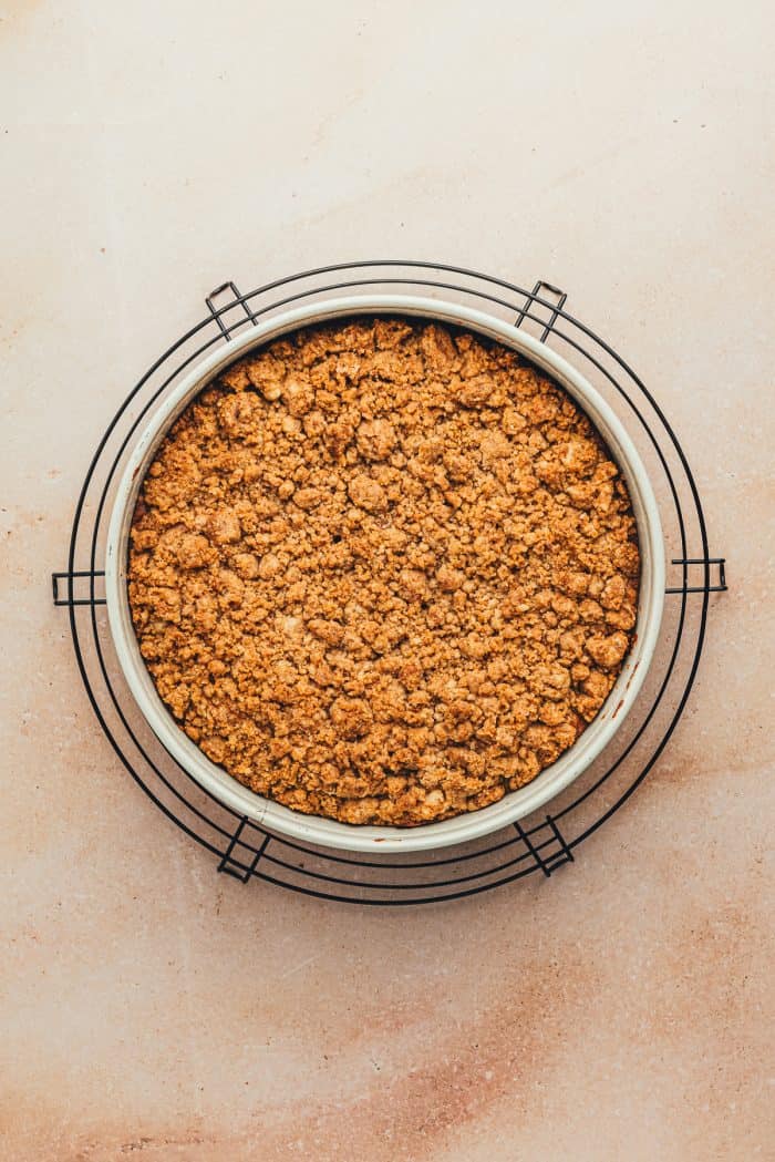 A baked coffee cake on a cake pan on a cooling rack.