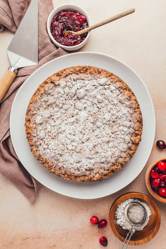 The whole coffee cake decorated with powdered sugar on a white plate.