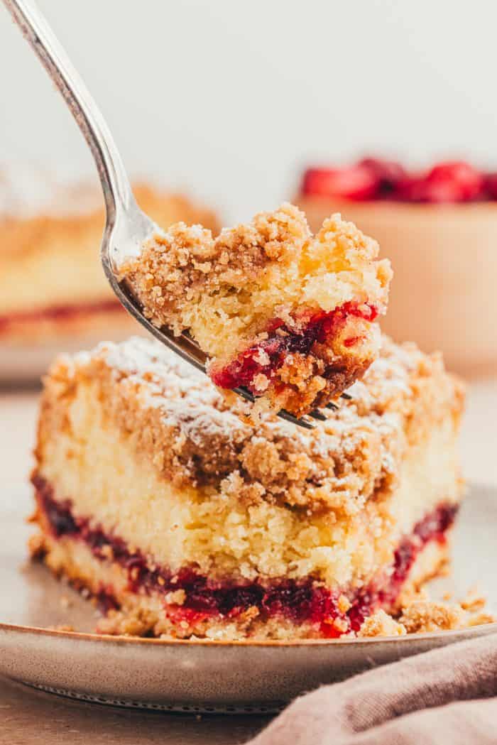 A plate with a slice of coffee cake with a fork with a bite of cake.