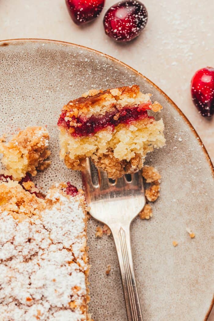 A plate with a bite of cranberry swirl coffee cake on a fork.