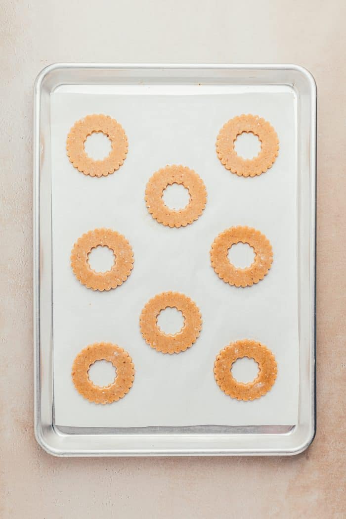 A cookie tray with parchment paper and unbaked Linzer cookies.