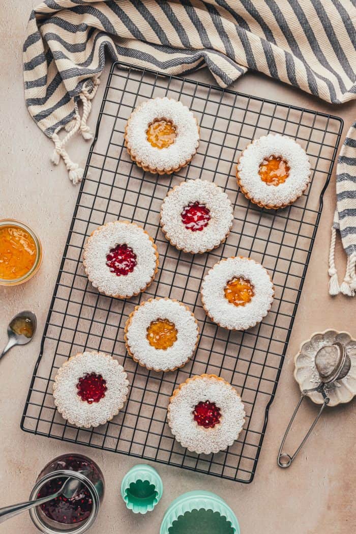 A cooling rack with Linzer cookies and tea towel.