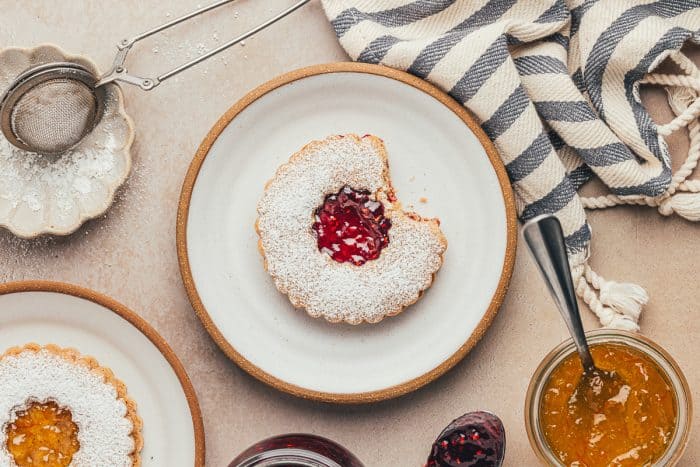 A plate with a Linzer cookie with a bite taken out of it.