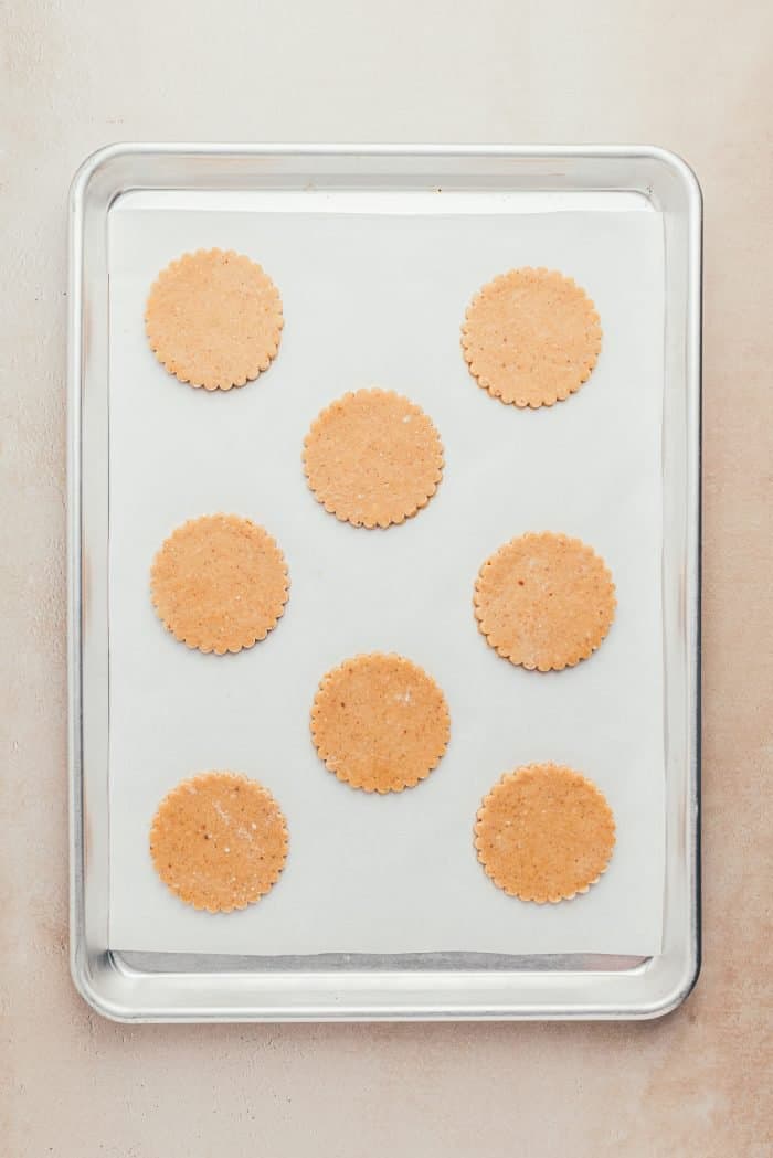 A cookie tray with parchment paper and unbaked Linzer cookies.