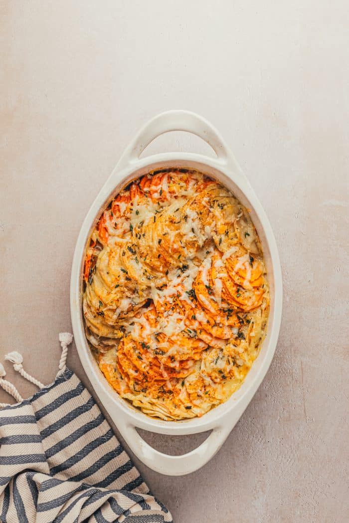 A baked root vegetable gratin in a white baking dish.