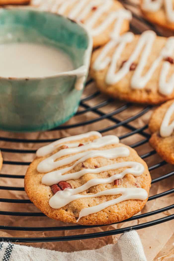 Glazed drop cookies with nuts on a cooling rack with a container of glaze.