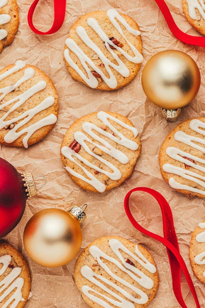 Spice drop cookies scattered on parchment paper with gold Christmas tree ornaments. 