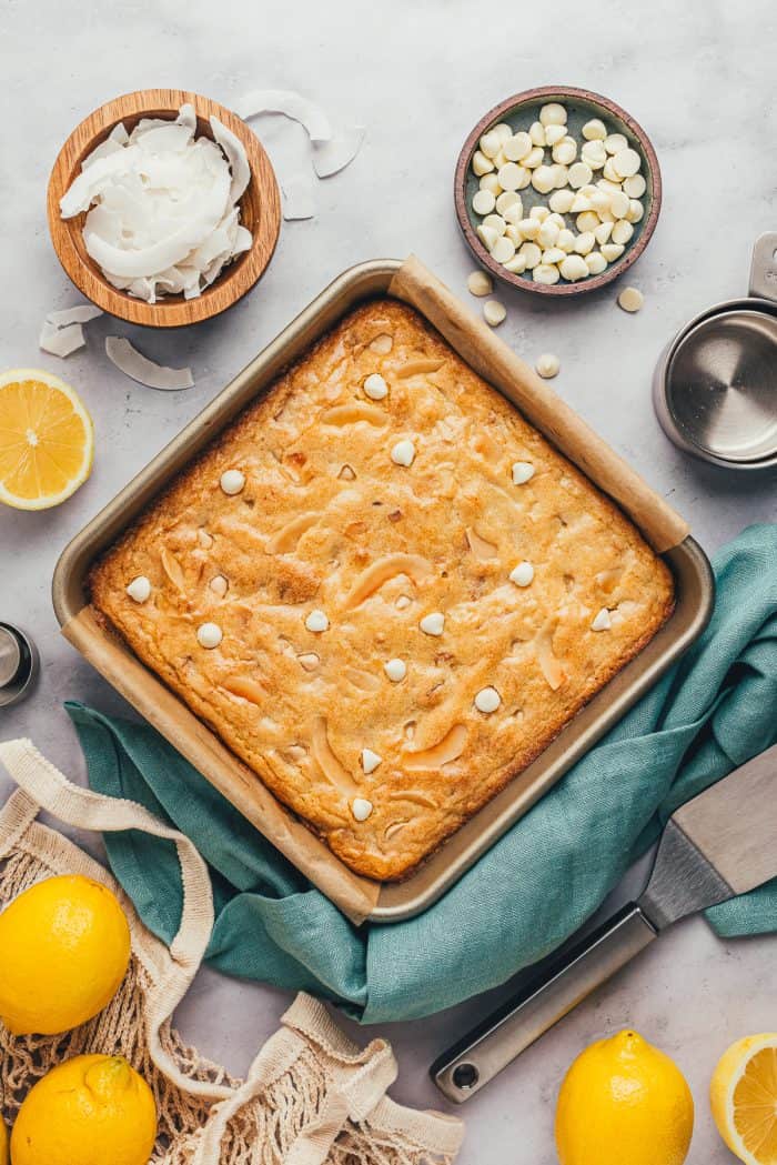 Lemon blondies in a square baking tray with ingredients surrounding them. 