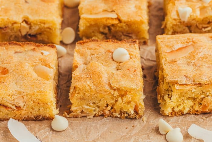 Lemon blondies in two rows with white chocolate chips scattered around them.