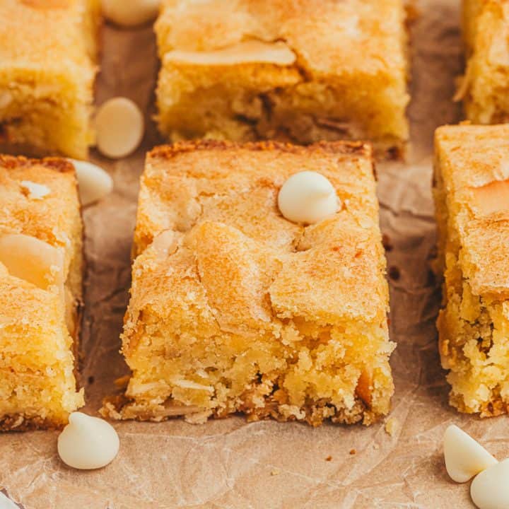 Lemon blondies in two rows with white chocolate chips scattered around them.