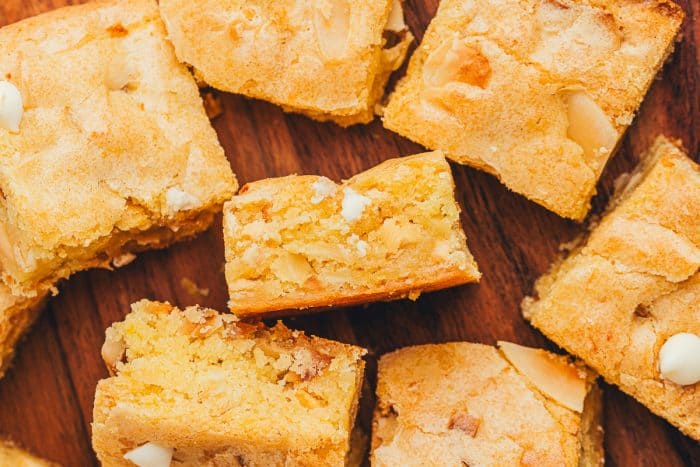 A variety of lemon blondies scattered over a wooden background.