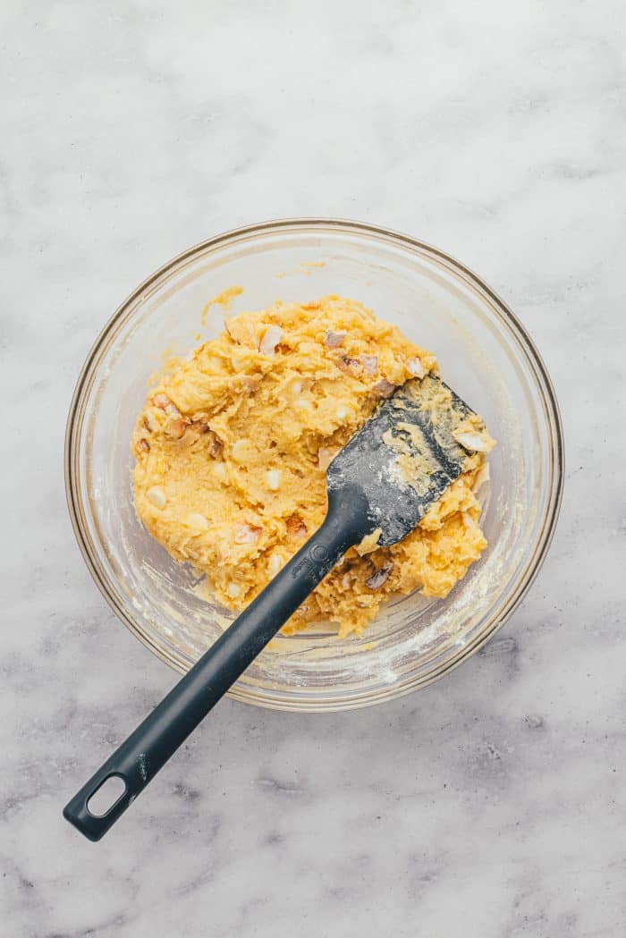 A glass bowl with the lemon blondie batter and a spatula.