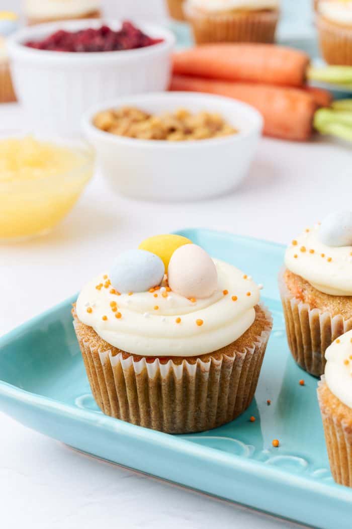 Decorated carrot cake cupcakes on a blue plate.