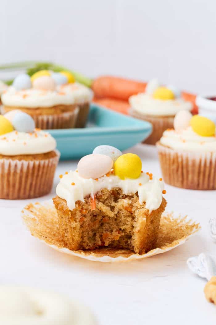 A carrot cake cupcakes with a bite taken out of it.