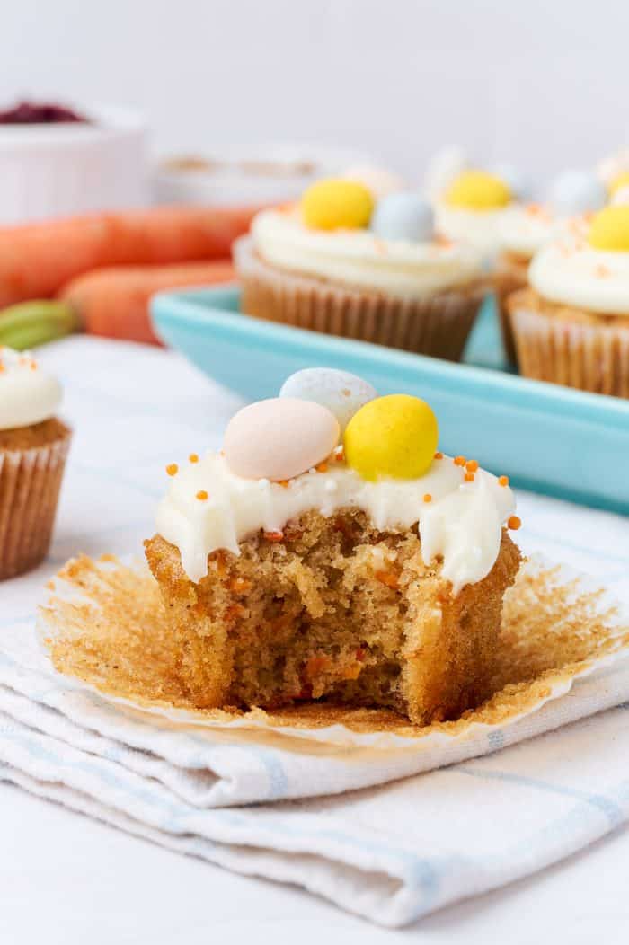 A carrot cake cupcakes with a bite taken out of it.