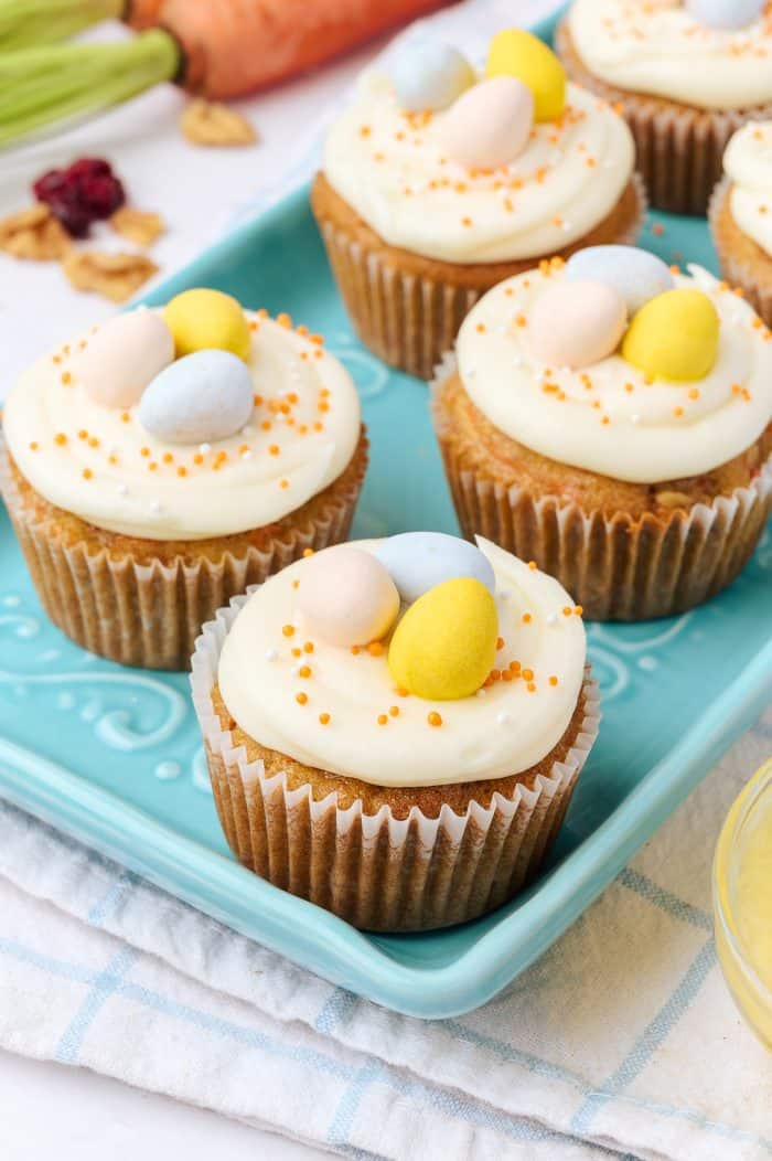 Decorated carrot cake cupcakes on a blue plate.