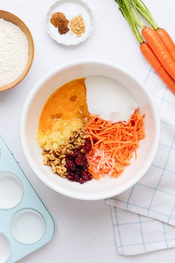 A white mixing bowl with all of the ingredients to make the carrot cake cupcakes batter.