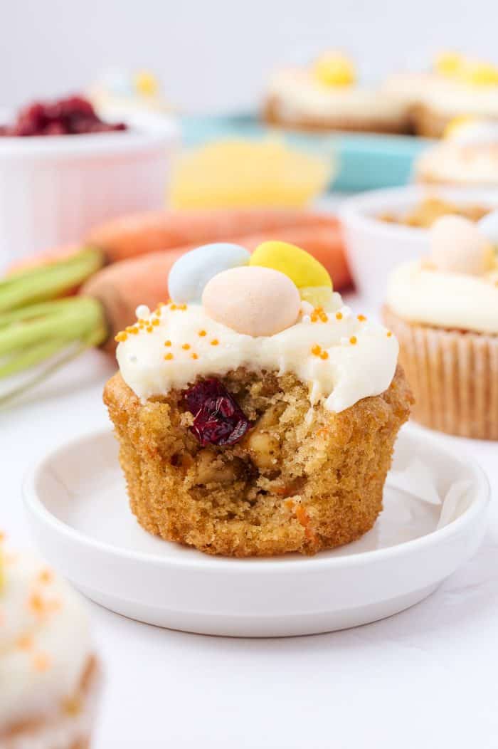 A decorated carrot cake cupcake on a small white plate.