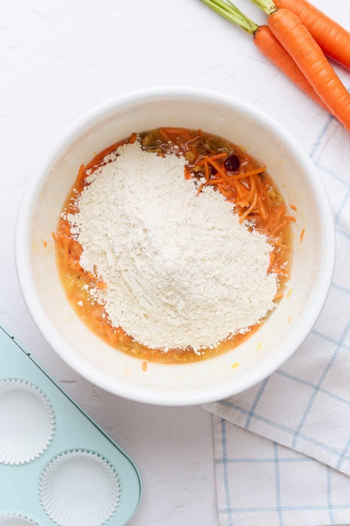 A white mixing bowl with flour added to the wet ingredients.