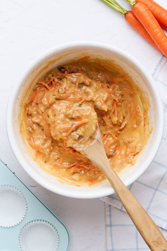 A white mixing bowl with the mixed carrot cake cupcakes batter.