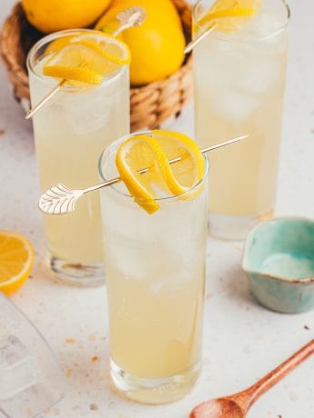 An image of three tall glasses with lemon elderflower mocktail and garnished with lemon slices.