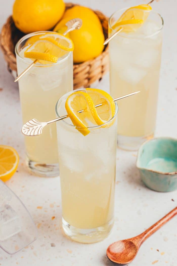 An image of three tall glasses with lemon elderflower mocktail and garnished with lemon slices.