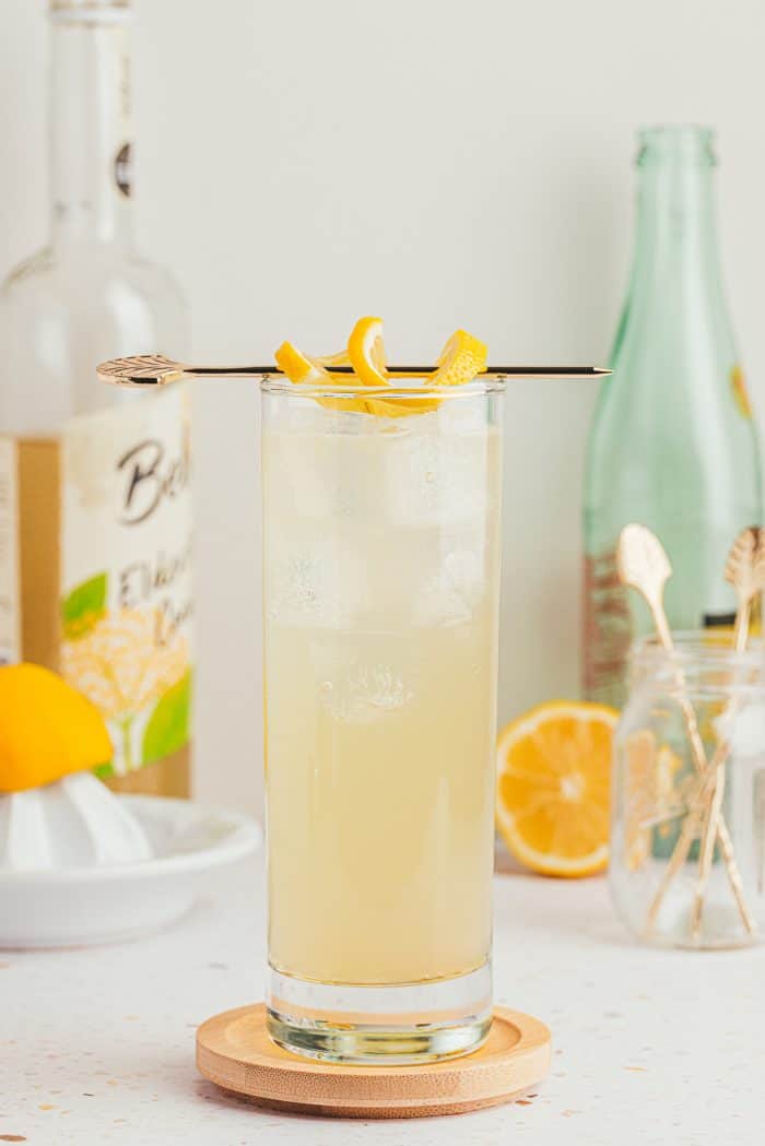 An image of a tall glass with lemon elderflower mocktail and garnished with lemon slices.