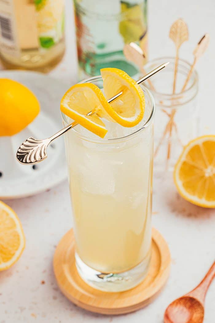 An image of a tall glass with lemon elderflower mocktail and garnished with lemon slices.