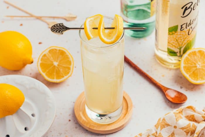 An image of a tall glass with lemon elderflower mocktail and garnished with lemon slices.