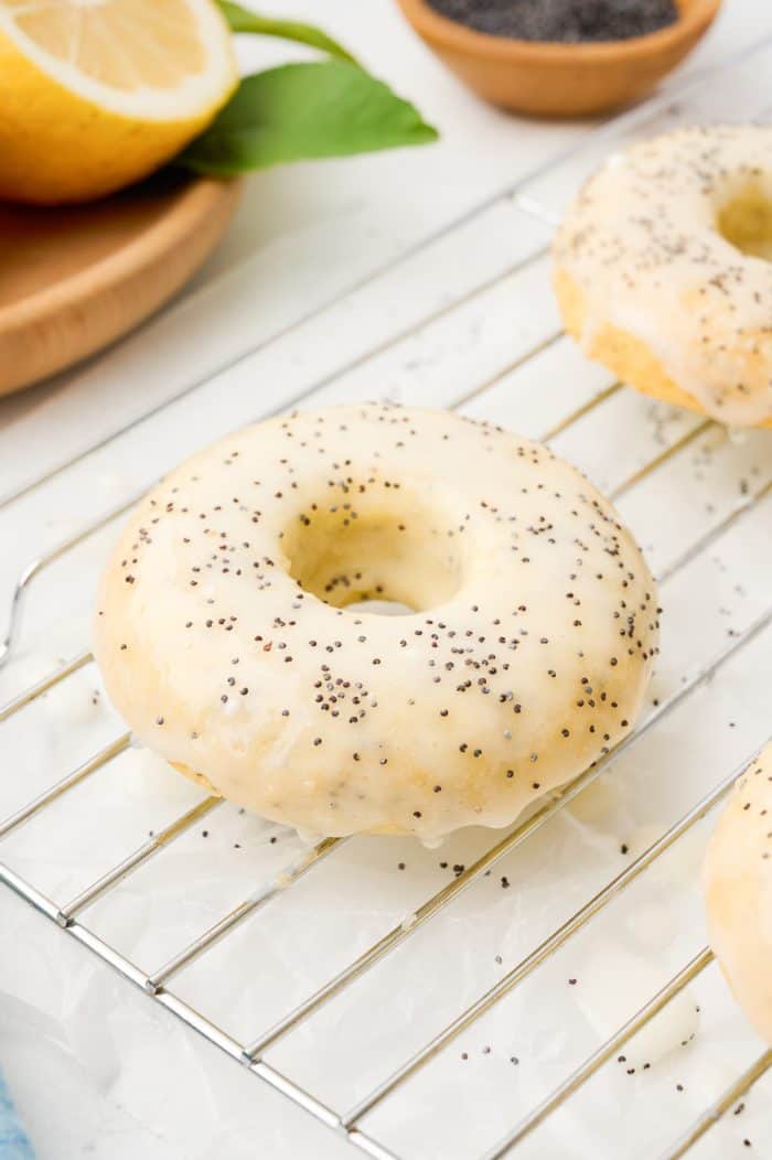 A lemon poppyseed donuts on a cooling rack.