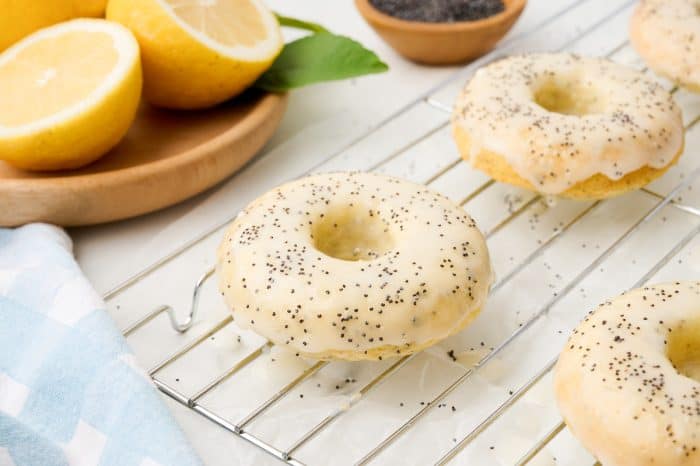 Lemon poppyseed donuts on a cooling rack.