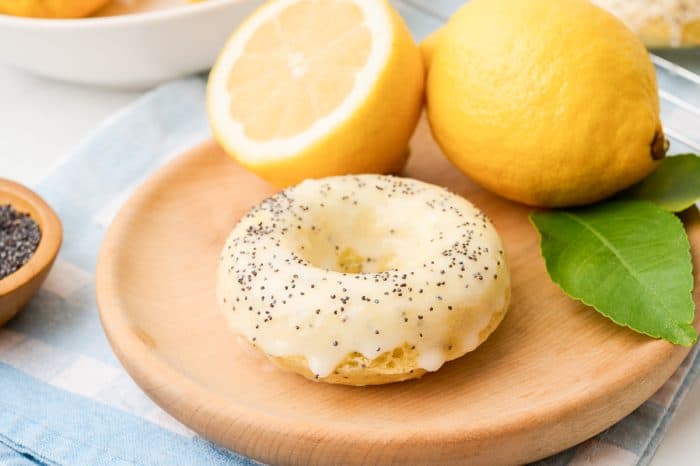 A lemon poppyseed donut on a wooden tray.