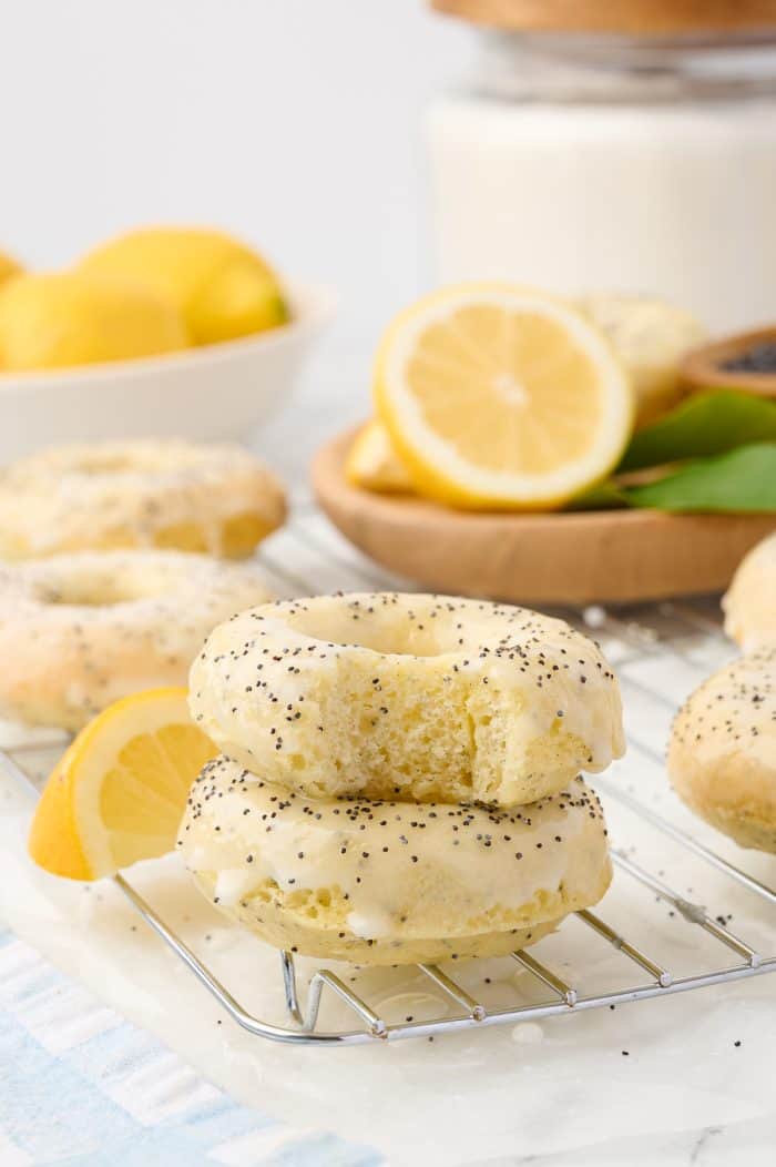 Two lemon poppyseed donuts stacked on a cooling rack.