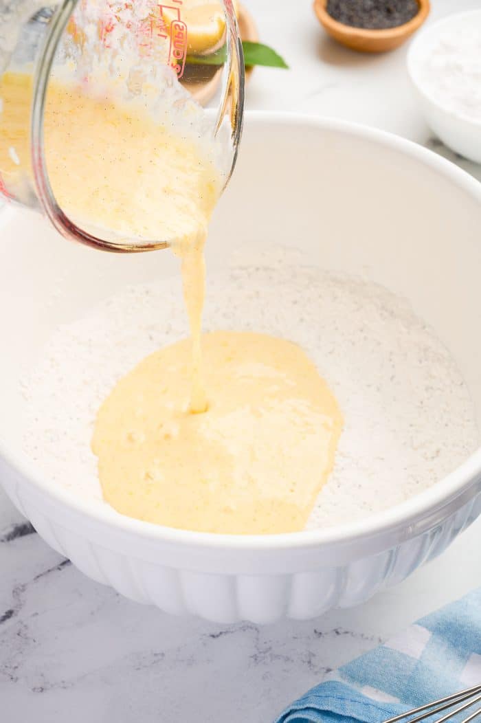 The wet batter being poured into the dry ingredients in a white bowl.