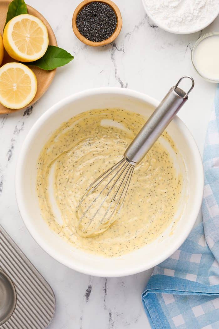 Lemon poppyseed donuts batter in a mixing bowl with a whisk.