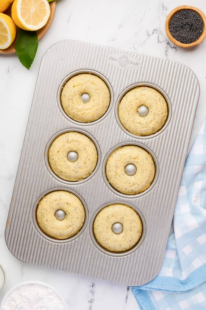 Baked lemon donuts in a metal donut baking pan.