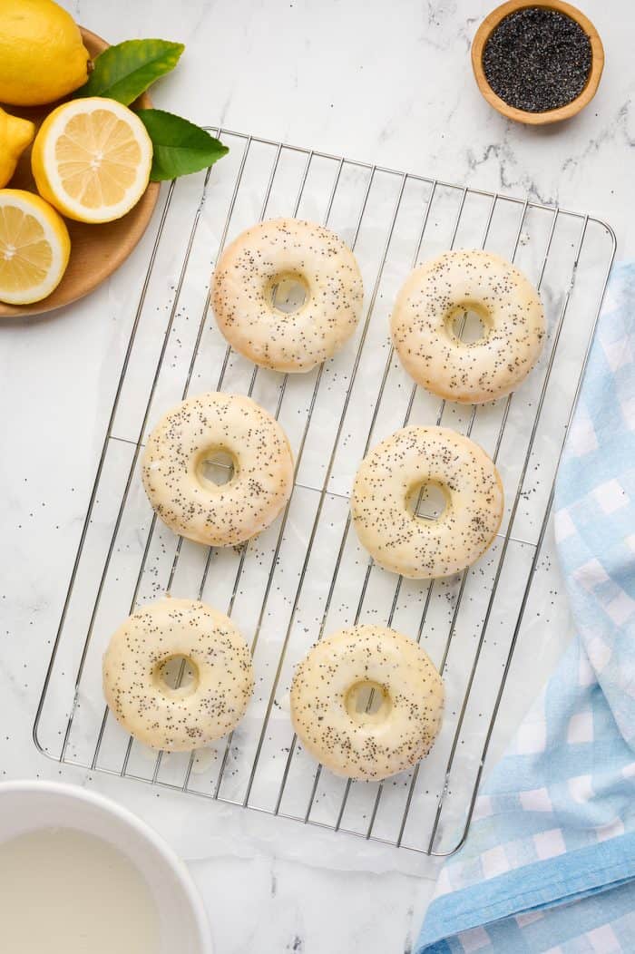 Baked lemon donuts on a cooling rack with lemon glaze.