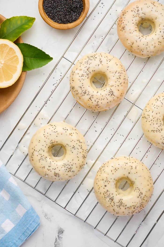 Lemon poppyseed donuts on a cooling rack.