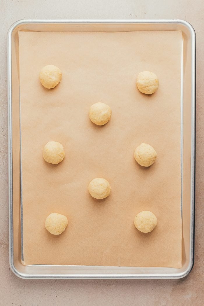 A cookie sheet with unbaked lemon sugar cookies on it.