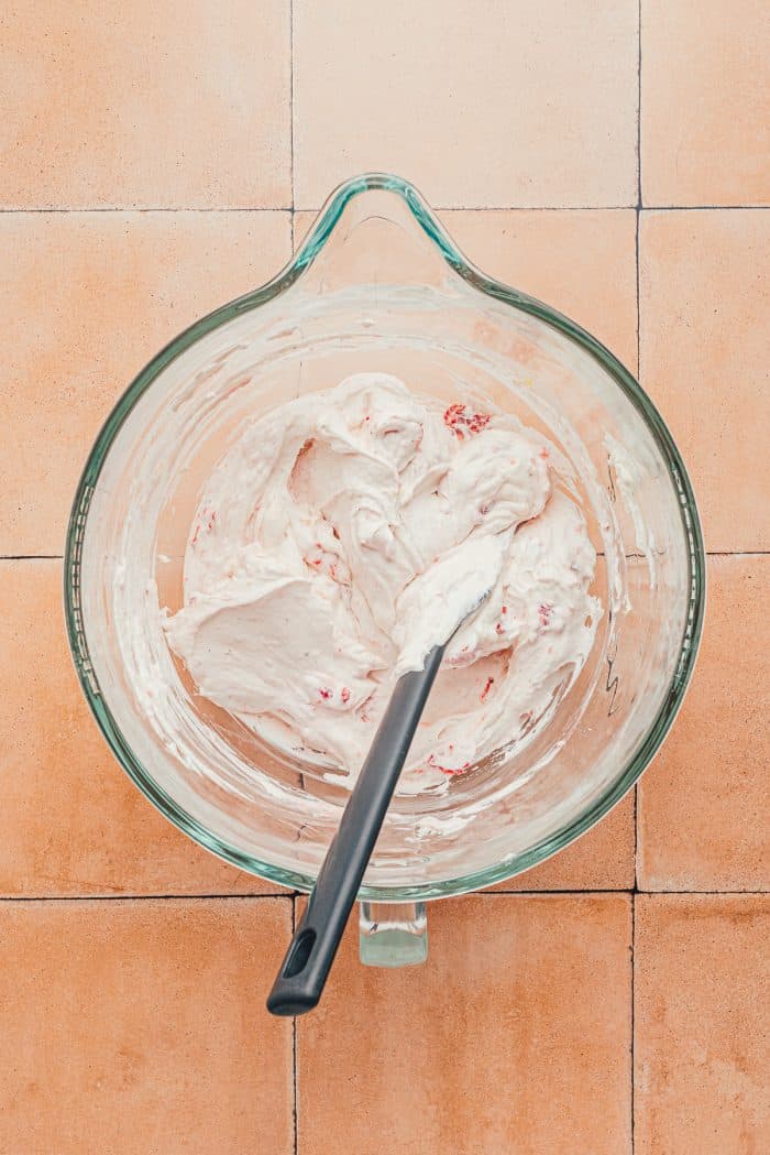 The heavy cream mixture mixed with the strawberry mixture in a glass bowl.