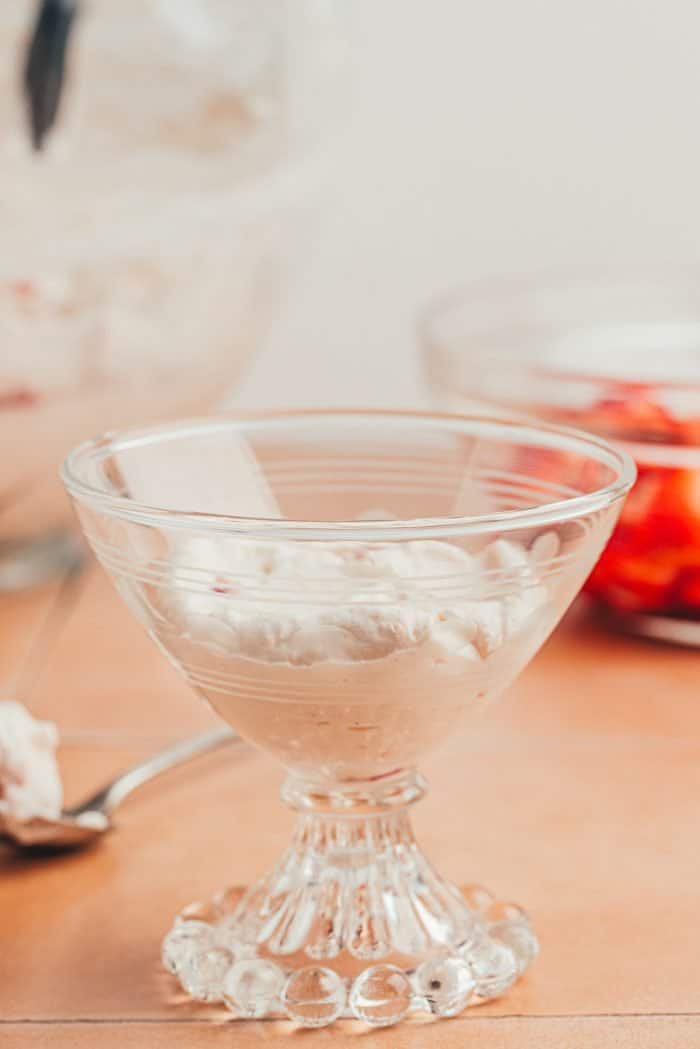 A scoop of strawberry fool in a glass serving dish.