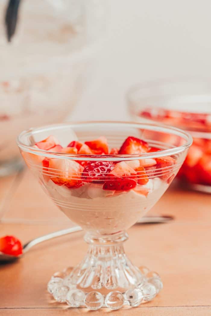 A layer of strawberries added to the strawberry fool in a glass serving dish.